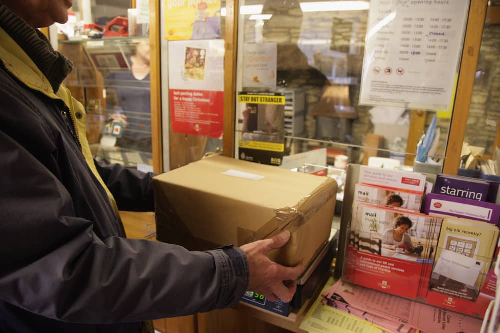 Customers weigh packages at the post office.