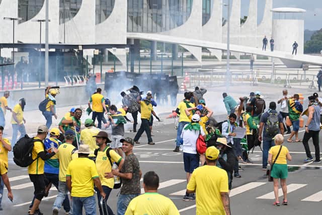 Supporters of Brazilian former President Jair Bolsonaro clash with the police during a demonstration outside the Planalto Palace in Brasilia on January 8, 2023. - Brazilian police used tear gas Sunday to repel hundreds of supporters of far-right ex-president Jair Bolsonaro after they stormed onto Congress grounds one week after President Luis Inacio Lula da Silva's inauguration, an AFP photographer witnessed. (Photo by EVARISTO SA / AFP) (Photo by EVARISTO SA/AFP via Getty Images)