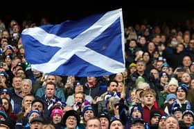 A Scotland fan waves a national flag as they enjoy the pre-match atmosphere prior to a Six Nations Rugby match at Murrayfield Stadium