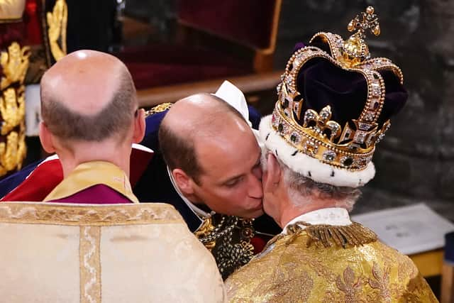 Prince William, Prince of Wales kisses his father, King Charles III, wearing St Edward's Crown, during the King's Coronation Ceremony inside Westminster Abbey on May 6, 2023 in London, England. The Coronation of Charles III and his wife, Camilla, as King and Queen of the United Kingdom of Great Britain and Northern Ireland, and the other Commonwealth realms takes place at Westminster Abbey today. Charles acceded to the throne on 8 September 2022, upon the death of his mother, Elizabeth II. (Photo by Yui Mok  - WPA Pool/Getty Images)