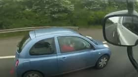 Woman applies make-up while driving along the motorway.