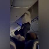 Passengers help man from overhead bin after 'strong turbulence'.