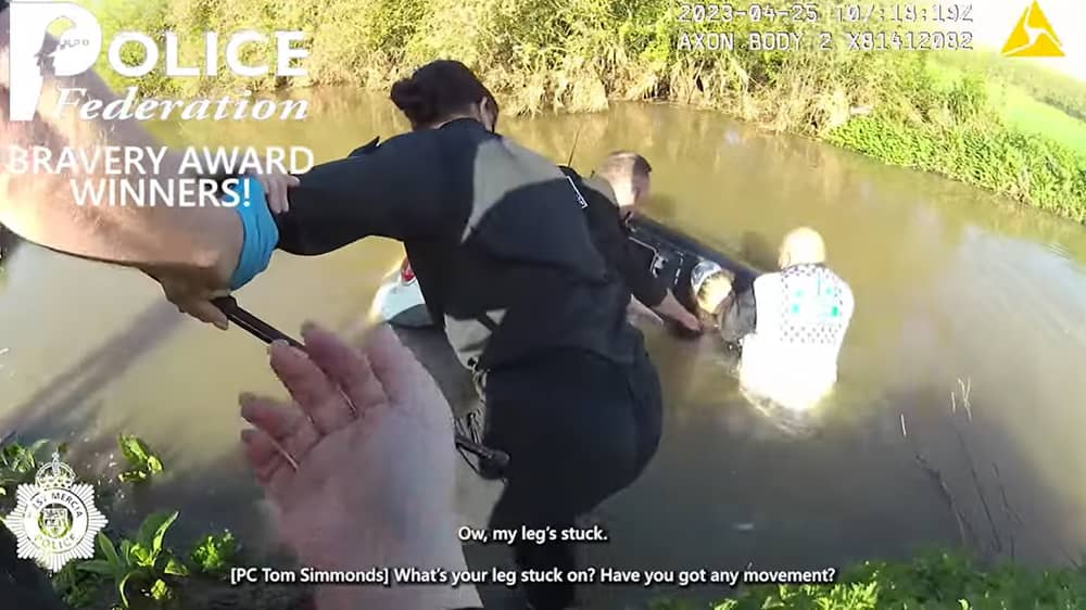 Woman is rescued from neck-level flood water in submerged car.
