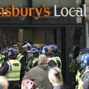 Police gather outside the Sainsbury’s local that was targeted by looters. 