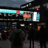 Rail travellers look at an electronic information board displaying train time information outside Euston Station in London. Photo: JUSTIN TALLIS/AFP via Getty Images
