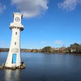 A white clock tower surrounded by water in a serene location