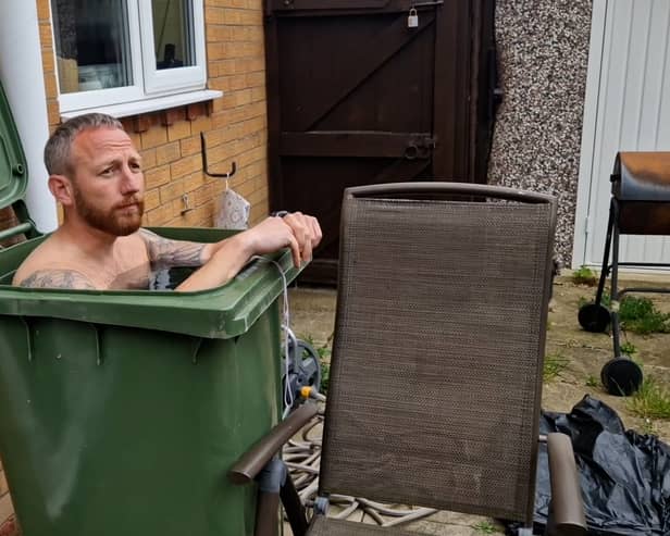 Martin Lynch taking a cold water bath in his wheelie bin