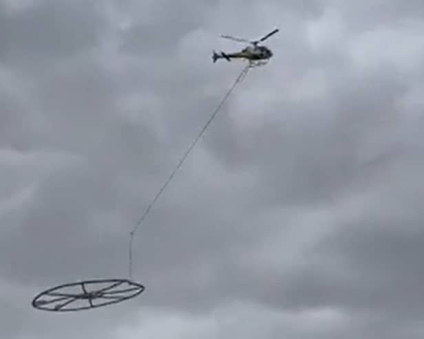 Helicopter carrying large metal circle.