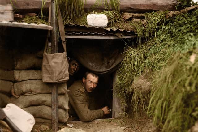 Two New Zealand soldiers look out of a dugout at the front line, at Hebuterne in France. The photograph was taken on May 13, 1918 by Henry Armytage Sanders. The sign above the entrance reads; 'The Diggers rest. Board and residence. Cold showers when it is wet. Herr Fritz's Orchestra plays at frequent intervals.'
Image: Tom Marshall (PhotograFix) EMN-201021-173511001