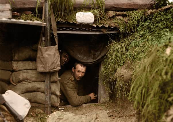 Two New Zealand soldiers look out of a dugout at the front line, at Hebuterne in France. The photograph was taken on May 13, 1918 by Henry Armytage Sanders. The sign above the entrance reads; 'The Diggers rest. Board and residence. Cold showers when it is wet. Herr Fritz's Orchestra plays at frequent intervals.'

Image: Tom Marshall (PhotograFix) EMN-201021-173511001