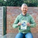 Jeff Brown with a copy of his fundraising travel book EMN-200112-114754001