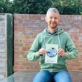 Jeff Brown with a copy of his fundraising travel book EMN-200112-114754001