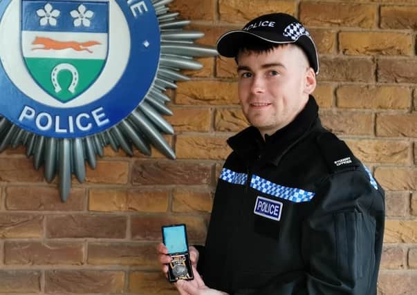 Pc Dan Challis holding a war medal won by his great-great-great grandfather, Pc John William Stephens, aka Pc Tubby EMN-200312-180744001