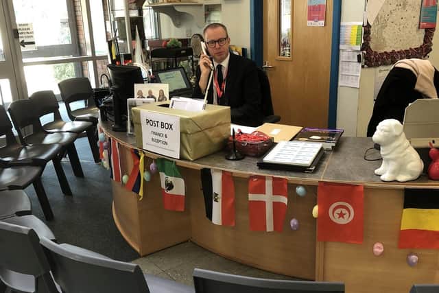 Long Field Academy principal Chris Haggett mans the reception phones today with an appropriate exculsion zone to limit spread of coronavirus EMN-200323-120732001