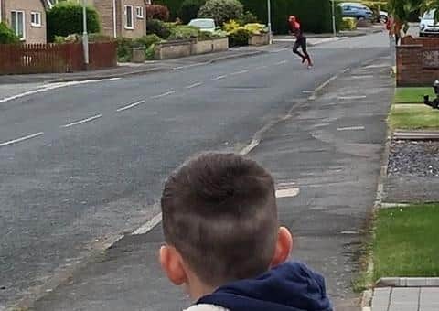 Spiderman, aka Melton sports coach Thomas Craig, patrols Edendale Road in Melton, to the delight of resident Theo Poyzer EMN-201205-173015001