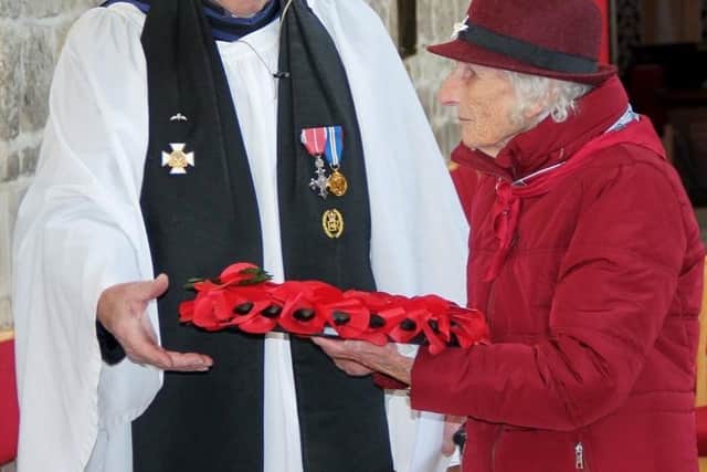 Freda Kemp, widow of veteran Lew Kemp who was wounded at Arnhem, laying a wreath at the 151/156 Parachute Battalion's memorial plaques in St. Mary's Church, Melton Mowbray, assisted by Padre The Reverend Brian McAvoy. EMN-211013-091757001