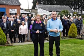 Mick and Joan on the first tee, supported by the members gathered in the background.