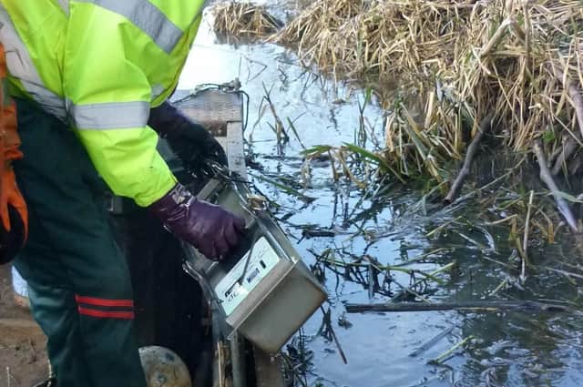 Members of Melton & Oakham Waterways Society remove a steel coinbox, believed to have been stolen from the Wilton Road toilet block, from the River Eye at Melton EMN-220214-120247001