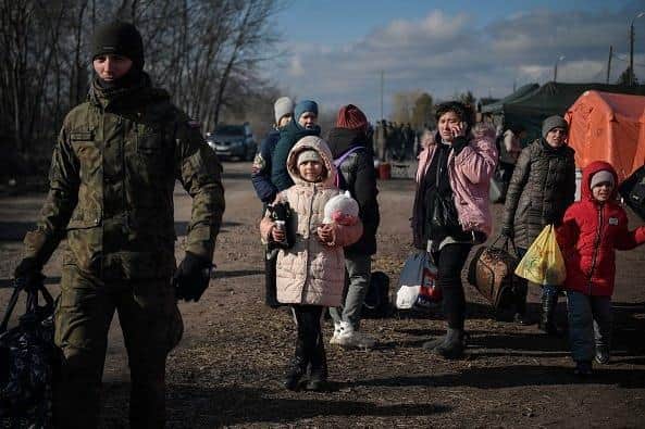 A Polish soldier helps families to carry their belongings after crossing the Ukrainian-Polish border at the Medyka border crossing, southeastern Poland, on March 10, 2022.(Photo by Louisa GOULIAMAKI / AFP) (Photo by LOUISA GOULIAMAKI/AFP via Getty Images) EMN-221003-161813001