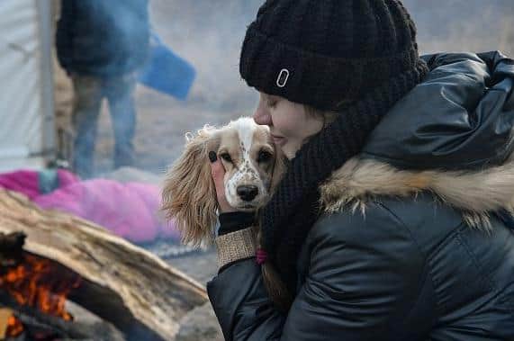 Anastazya from Kiev holds her dog as they warm by fire after crossing the Ukrainian border into Poland, at the Medyka border crossing, southeastern Poland on March 10, 2022. (Photo by Louisa GOULIAMAKI / AFP) (Photo by LOUISA GOULIAMAKI/AFP via Getty Images) EMN-221003-161823001