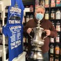 Jamie How, shows off the replica FA Cup trophy he is displaying in the window of his Melton shop, How Sweet EMN-211105-132331001