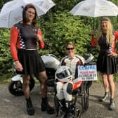 Claire Lomas wearing the racing leathers she will have on in Sunday's London Marathon with husband, Dan (left), and Stuart Hall, who will be running dressed as Grand Prix grid girls EMN-210929-131921001