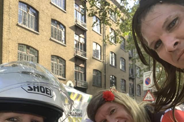 Claire Lomas poses with friend Stuart Hall and husband Dan, who were dressed as Grand Prix grid girls, at the halfway mark of Sunday's London Marathon EMN-210510-180415001