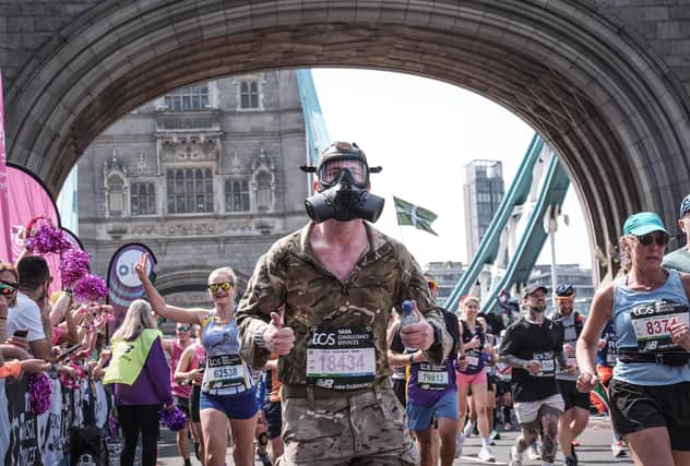 Tyler Bury runs across Tower Bridge in the 2025 London Marathon wearing a respirator and full military kit