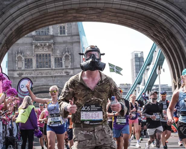 Tyler Bury runs across Tower Bridge in the 2025 London Marathon wearing a respirator and full military kit