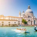 Beautiful view of traditional Gondola on Canal Grande with historic Basilica di Santa Maria della Salute in the background on a sunny day in Venice, Italy