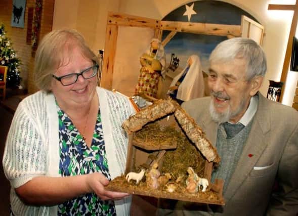 Carol Scarborough and John Phillips admire Ray Jackson's wooden crib creation at the Crib Festival in 2018