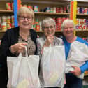 Storehouse manager, Siggy Atherton (left), with two of the volunteers holding food bags in the foodbank's shop