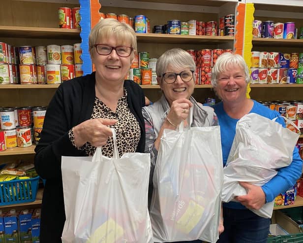 Storehouse manager, Siggy Atherton (left), with two of the volunteers holding food bags in the foodbank's shop