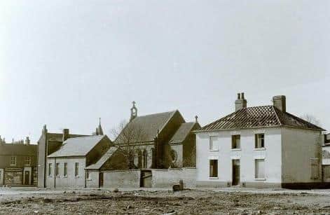 A photo from the mid-1900s of the rear of the St John The Baptist Catholic Church, with the old church hall and nun’s house (left) and presbytery (white house – right), which have since been demolished