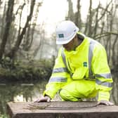 A Severn Trent employee inspects a drain near a river