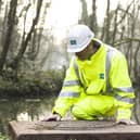 A Severn Trent employee inspects a drain near a river