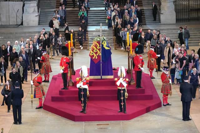 LONDON, ENGLAND - SEPTEMBER 14:  Members of the public file past the coffin of Queen Elizabeth II, draped in the Royal Standard with the Imperial State Crown and the Sovereign's orb and sceptre, lying in state on the catafalque in Westminster Hall, at the Palace of Westminster on September 14, 2022 in London, England. Members of the public are able to pay respects to Her Majesty Queen Elizabeth II for 23 hours a day from 17:00 on September 14, 2022 until 06:30 on September 19, 2022.  Queen Elizabeth II died at Balmoral Castle in Scotland on September 8, 2022, and is succeeded by her eldest son, King Charles III. (Photo by Yui Mok - WPA Pool/Getty Images)