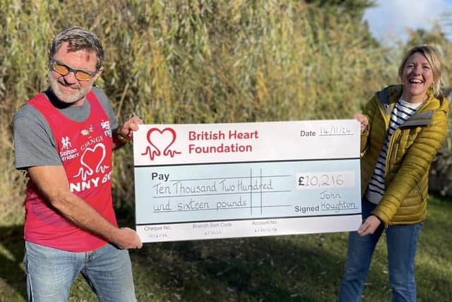 John Houghton presents a cheque to a representative of the British Heart Foundation following his marathon fundraising efforts