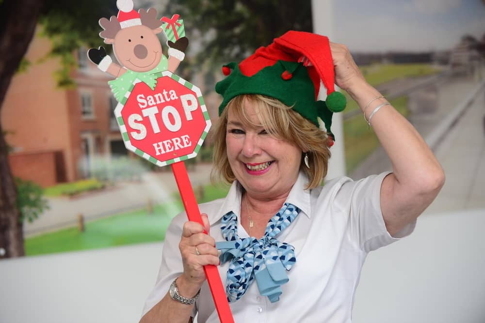 A Barratt and David Wilson Homes Sales Adviser with a Santa Stop Here sign
