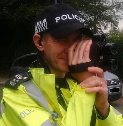 A Leicestershire police officer monitors a road with a speed gun