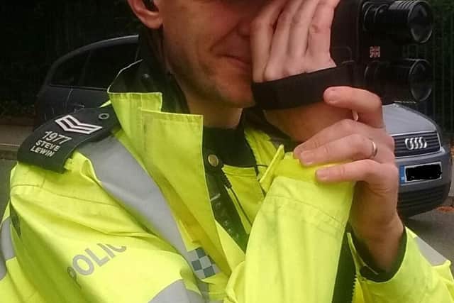 A Leicestershire police officer monitors a road with a speed gun