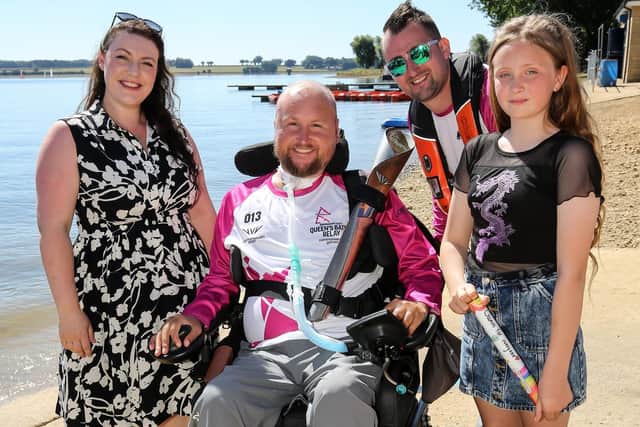 RUTLAND WATER, ENGLAND - JULY 10: Baton bearers Chris Farnsworth (2nd R) and Matt Hampson, with family and Rutland and Melton MP Alicia Kearns, hold the Queen's Baton during the Birmingham 2022 Queen's Baton Relay on a visit to Rutland Water, United Kingdom on July 10, 2022 in Rutland, England. (Photo by Nick England/Getty Images for Birmingham 2022 Queen's Baton Relay)