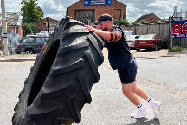 Fraser Mann, who runs the Steel Yard Gym and Fitness centre in Melton, warms up for the strongman event by lifting a giant tyre
