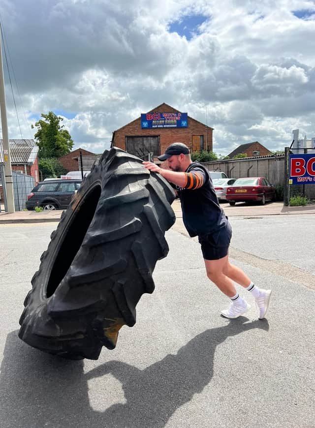 Fraser Mann, who runs the Steel Yard Gym and Fitness centre in Melton, warms up for the strongman event by lifting a giant tyre