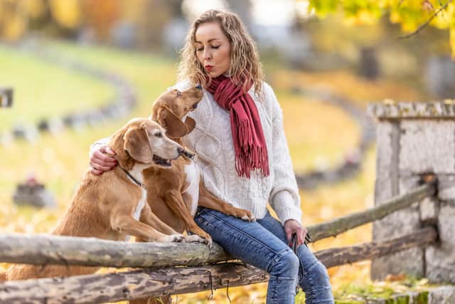 A young woman sits in the park with her dogs and shows them love (photo: Adobe)