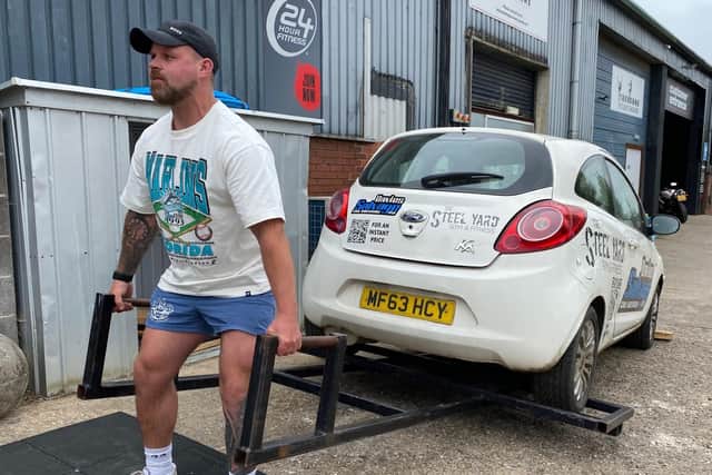 Fraser Mann demonstrates lifting a car - one of the strongman training facilities at The Steel Yard's new HQ