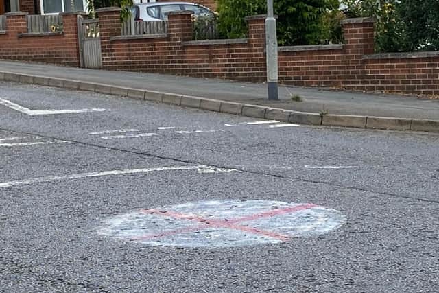 A red cross painted on a roundabout in Dalby Road, Melton Mowbray