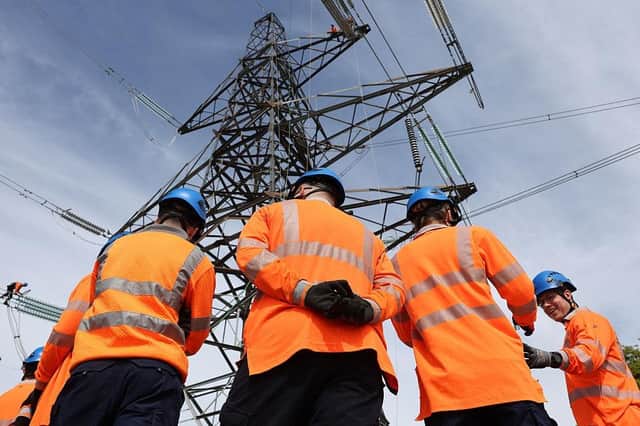 National Grid Overhead Line Apprentices stand below a electricity pylon at the National Grid training centre in Eakring, central England on April 28, 2025. (Photo by Darren Staples / AFP) (Photo by DARREN STAPLES/AFP via Getty Images)