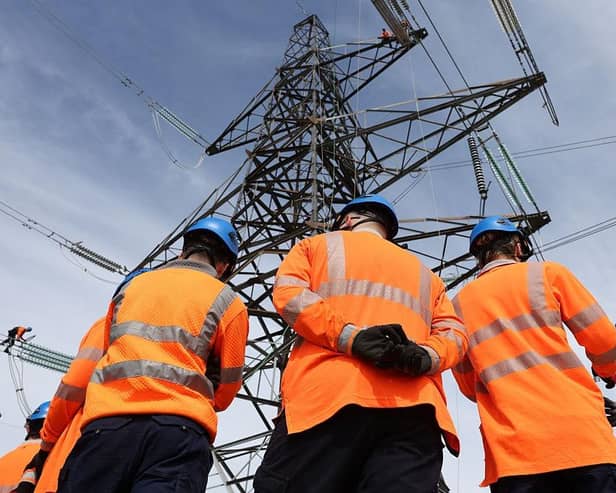 National Grid Overhead Line Apprentices stand below a electricity pylon at the National Grid training centre in Eakring, central England on April 28, 2025. (Photo by Darren Staples / AFP) (Photo by DARREN STAPLES/AFP via Getty Images)