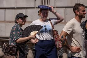 A woman fans herself as another shelters from the sun in London as temperatures near 35°C in May (Photo by Carl Court/Getty Images)